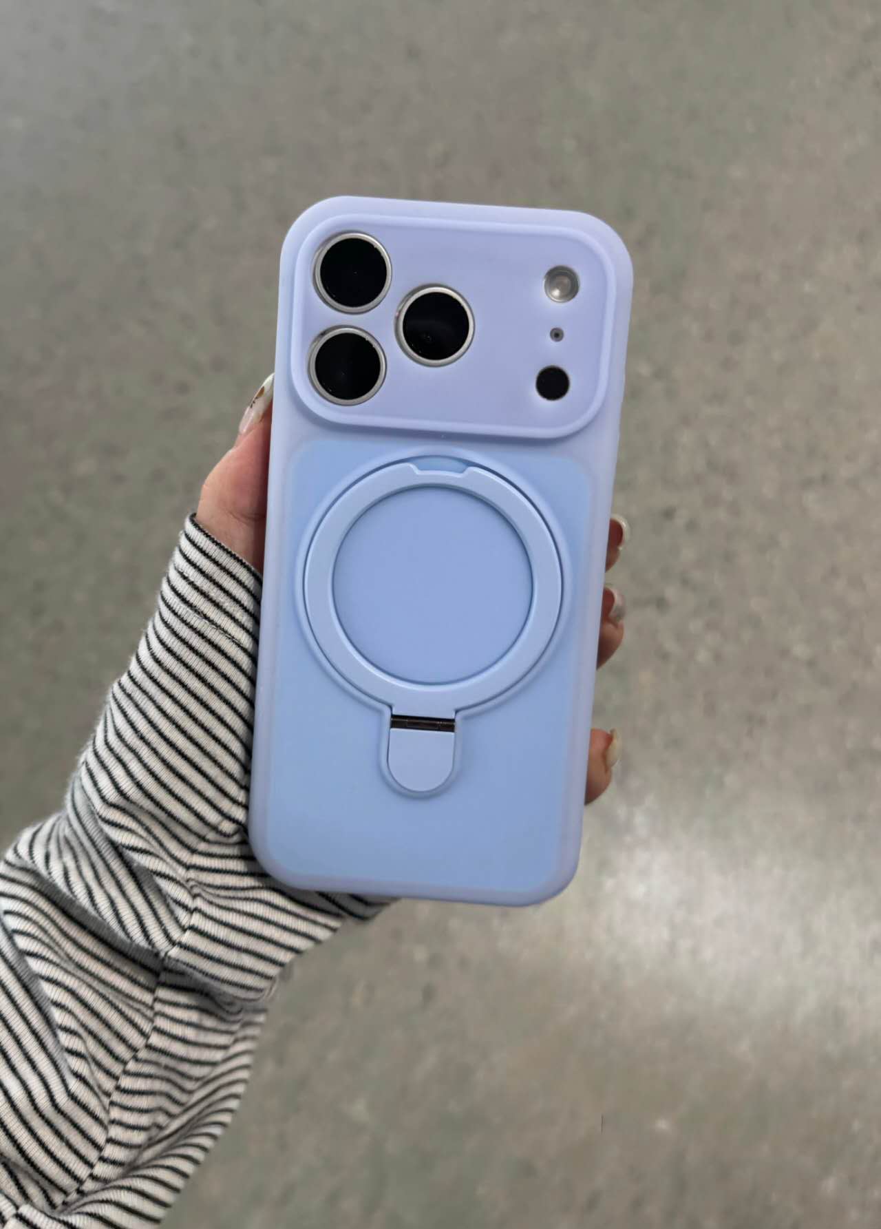 Blue phone case with integrated circular ring stand held in a hand