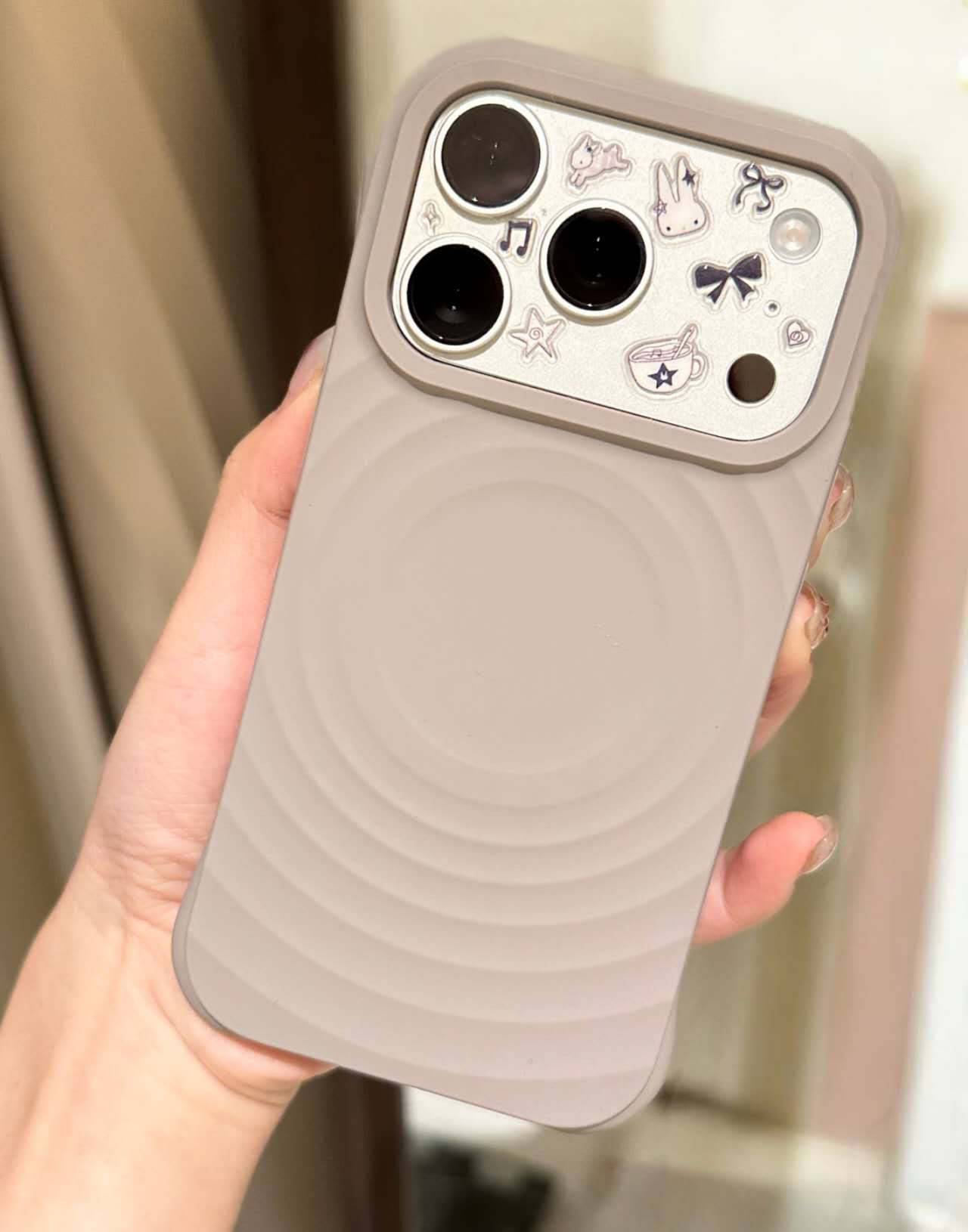 Close-up of a taupe ripple-pattern phone case held in a hand