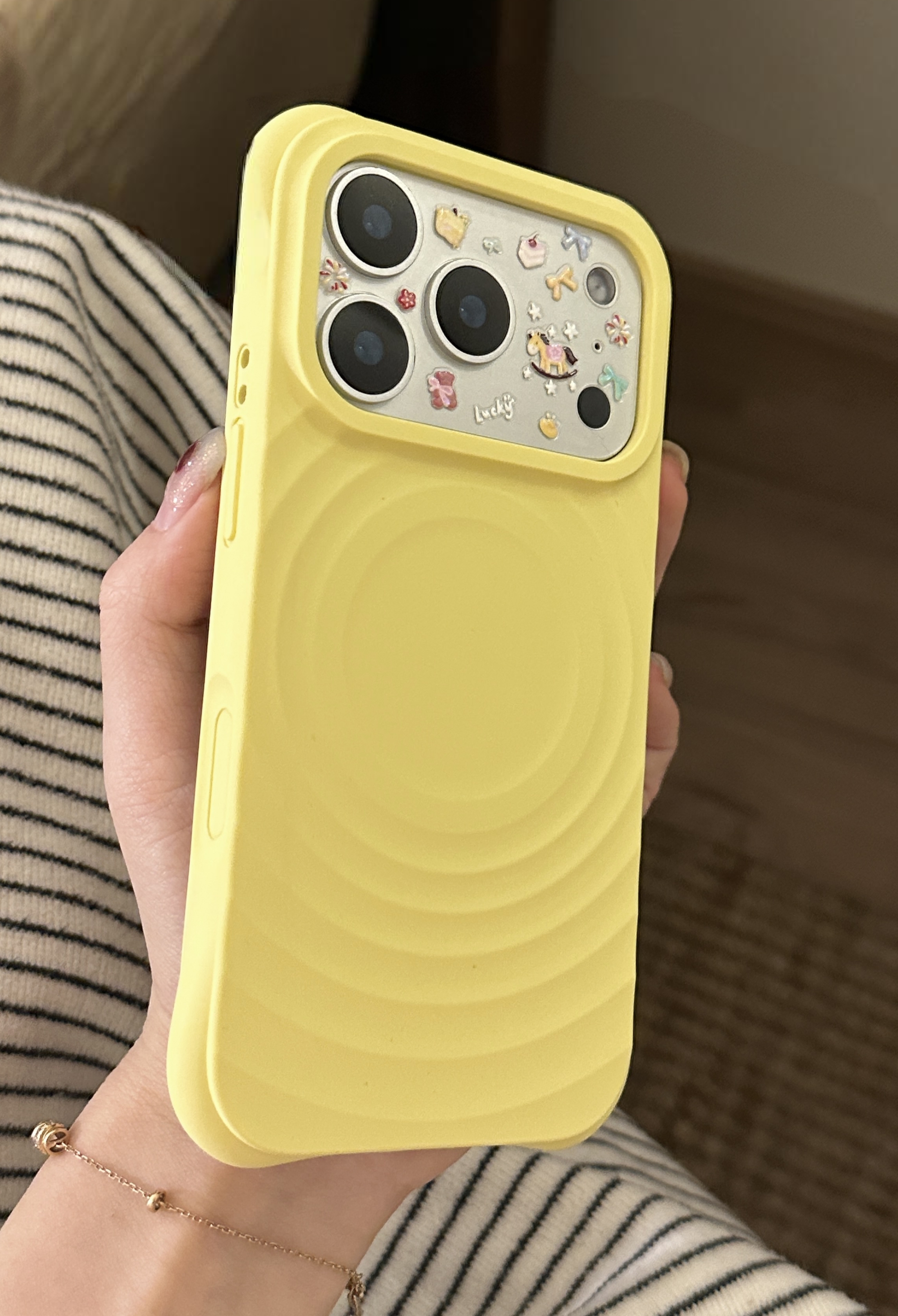 Yellow ripple-pattern phone case held in a hand